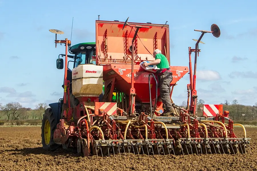 a professional landscaper loading seeds into the seed drill