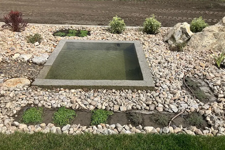 a designed hardscape featuring a small water retention area