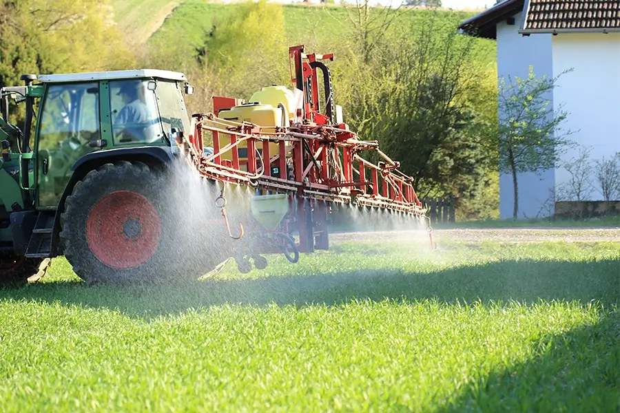 a tractor applying pesticide on a residential lawn