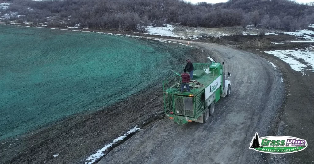 A green truck driving down a road surrounded by lush greenery.