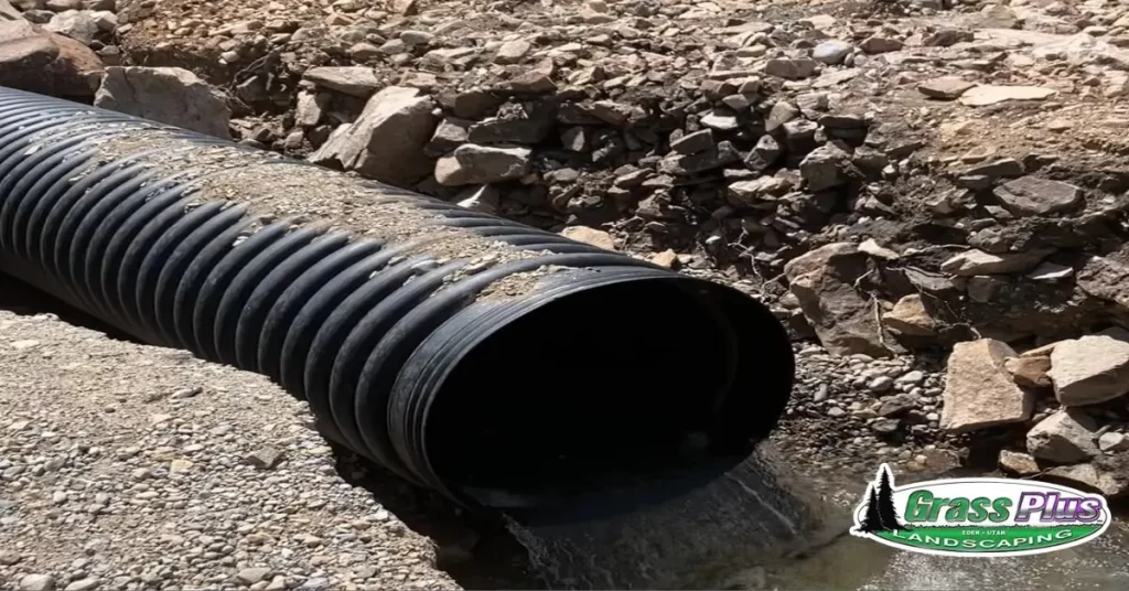 A black pipe draining water, serving as a drainage system.