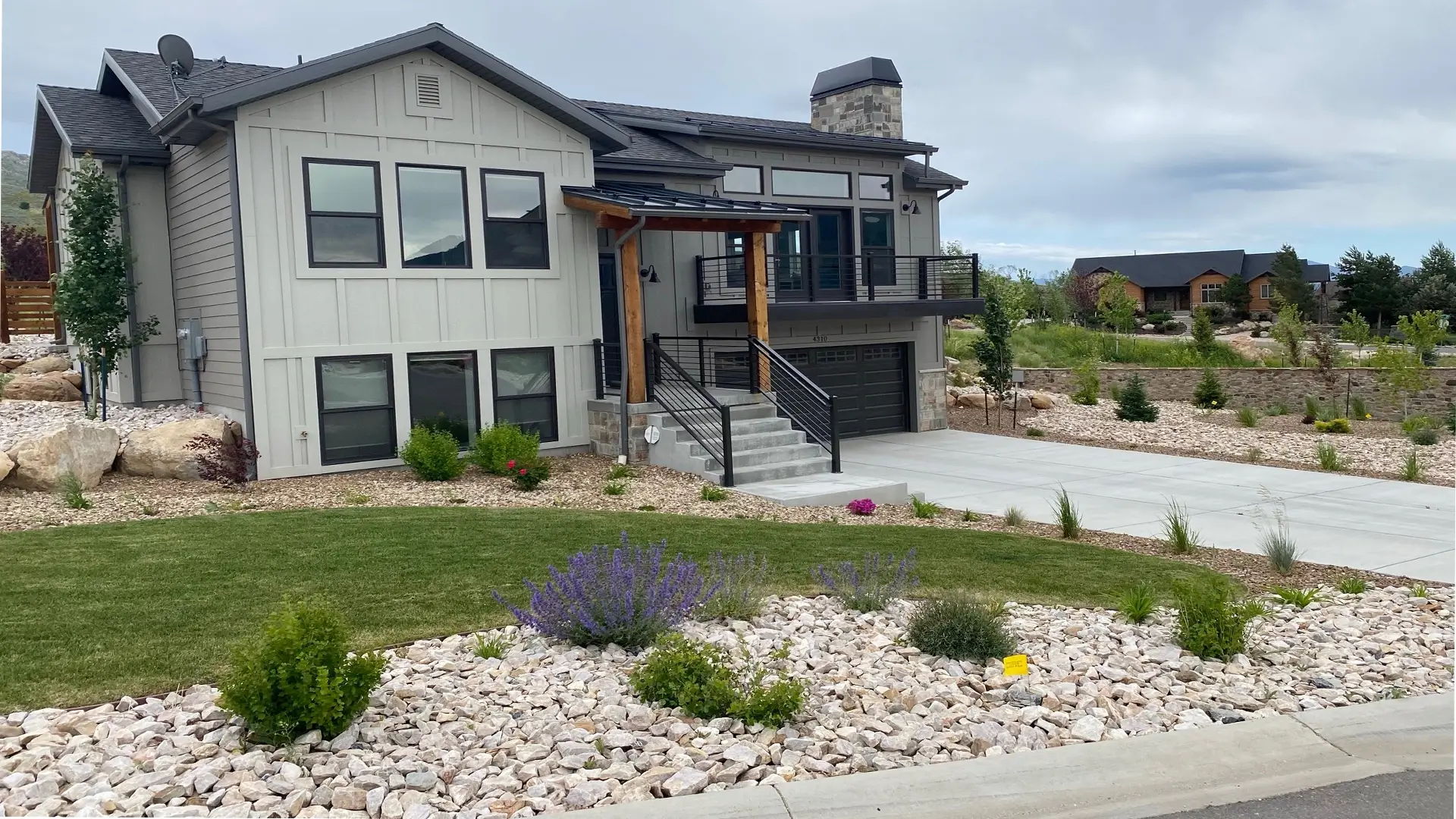 Modern home with clean xeriscaping, decorative rock, and well-maintained lawn by Grass Plus Inc.